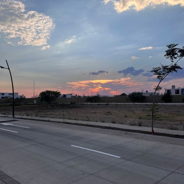 Terreno en venta en Residencial Mayorca con cielo anaranjado de atardecer y entorno urbano despejado.