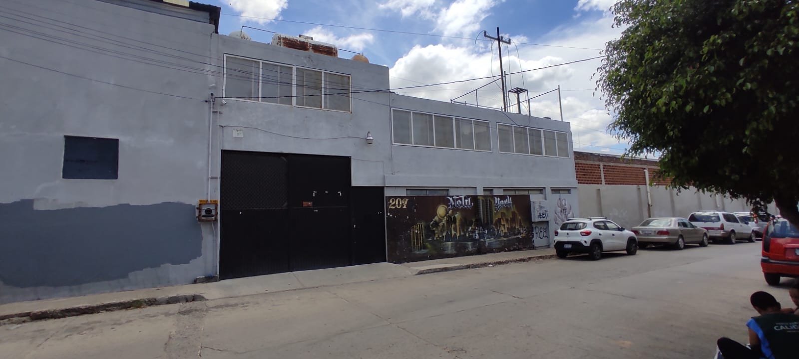 fachada de bodega Edificio gris con murales artísticos.