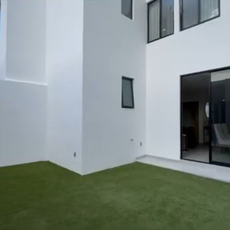 Patio moderno con césped y ventanas.