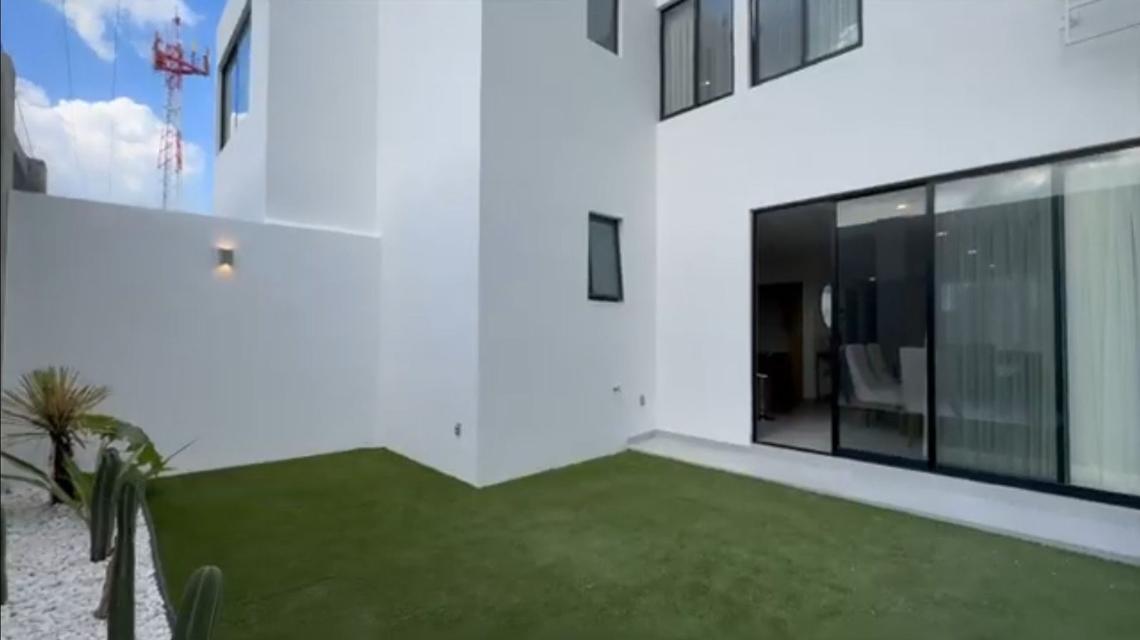 Patio moderno con césped y ventanas.