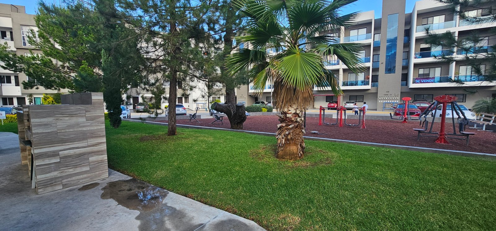 Parque con juegos infantiles y palmeras en zona residencial en León