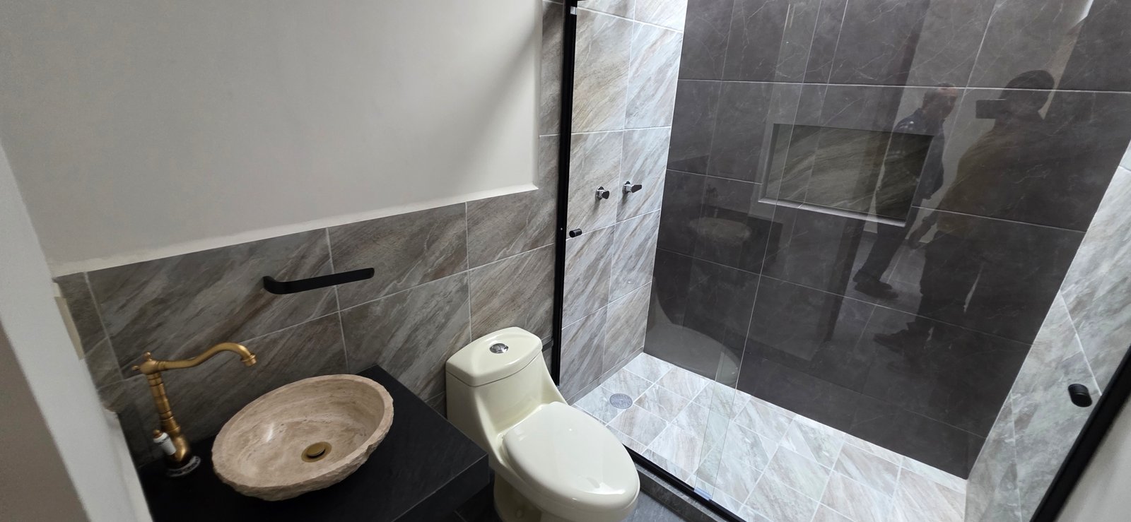Baño moderno con ducha y lavabo.