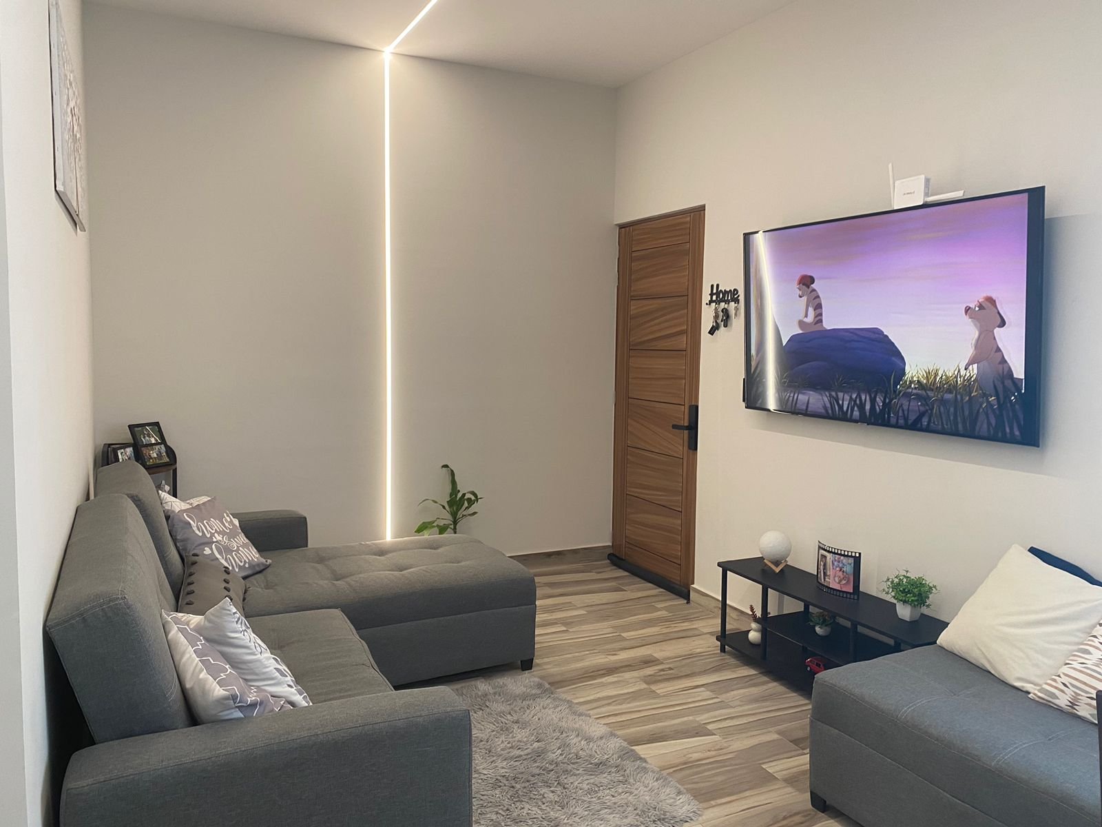 Sala moderna con sofá y televisor en departamento amueblado.