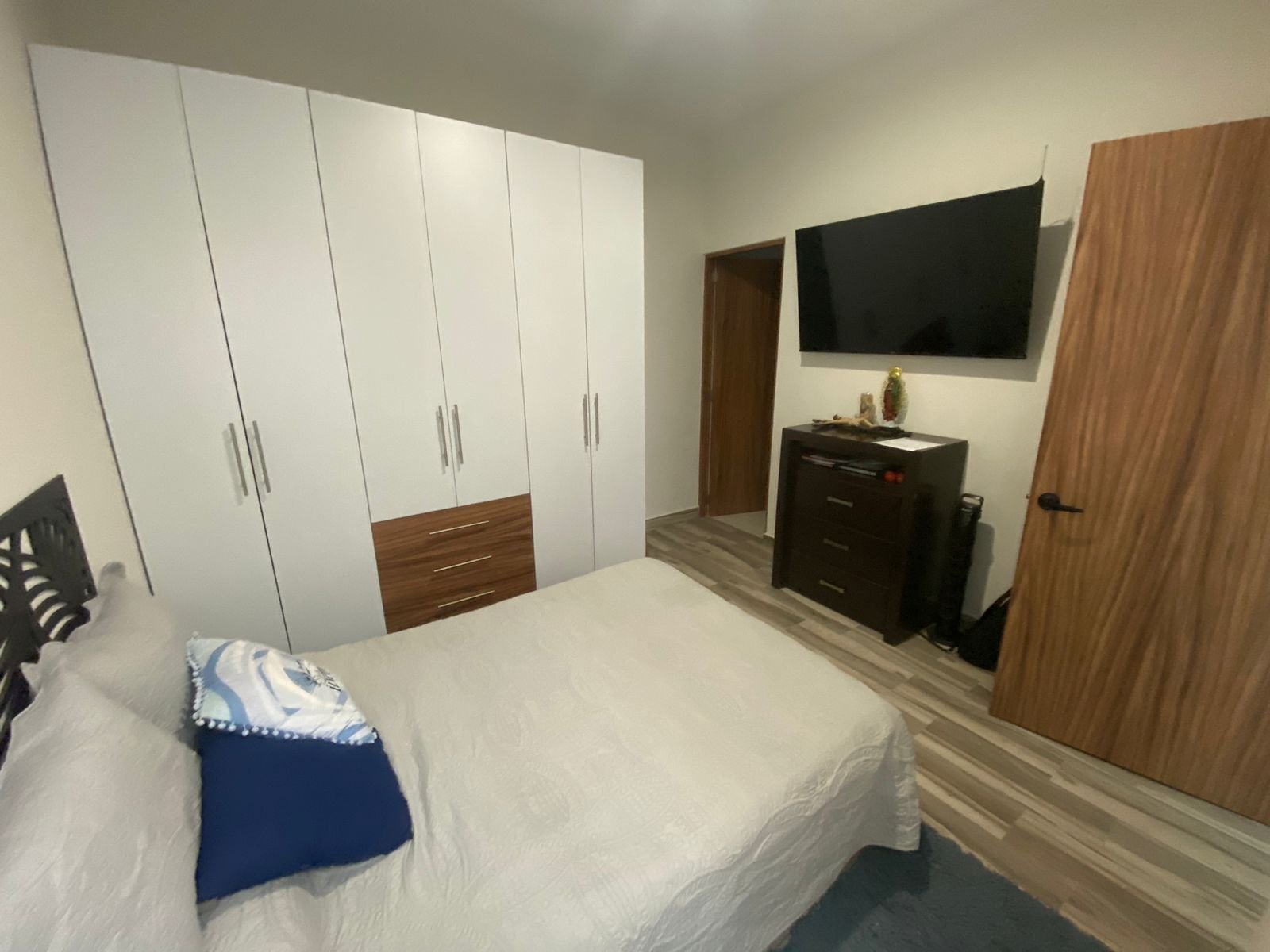 Habitación moderna con cama y armario en departamento amueblado.