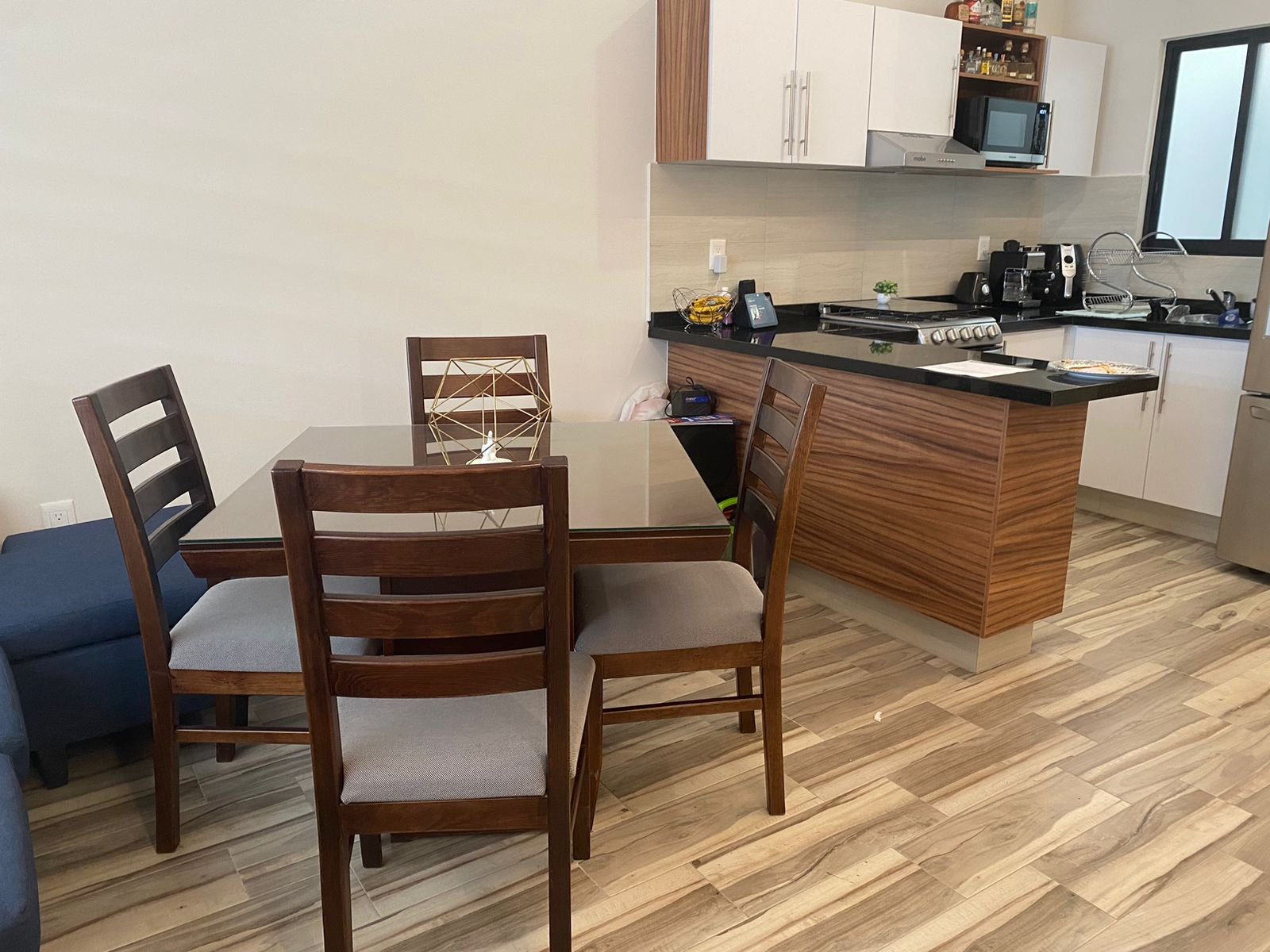 Cocina moderna con mesa de comedor y sillas en departamento amueblado.