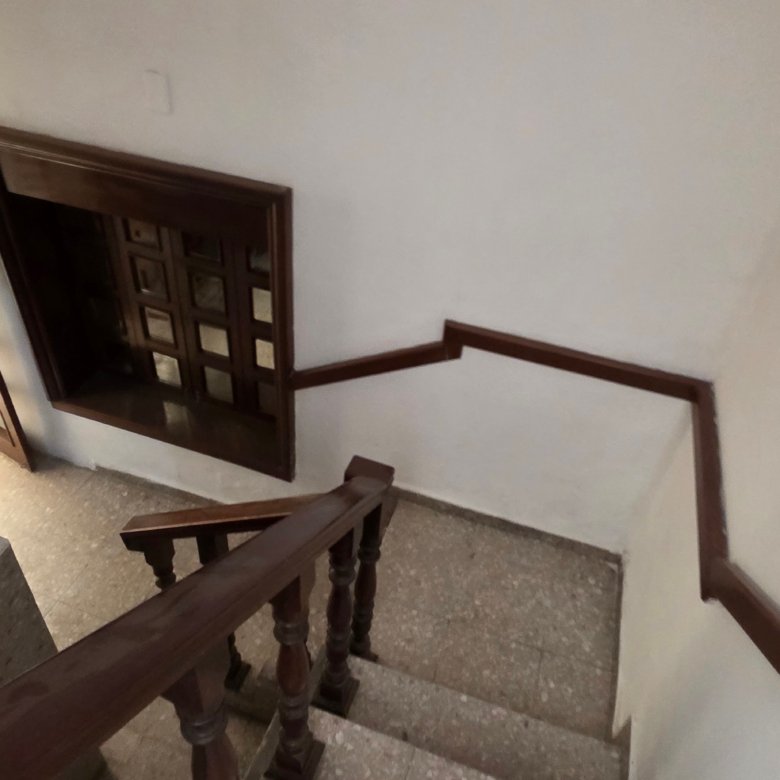 Detalle de escalera interior con barandilla de madera en propiedad profesional en Justo Sierra, León.