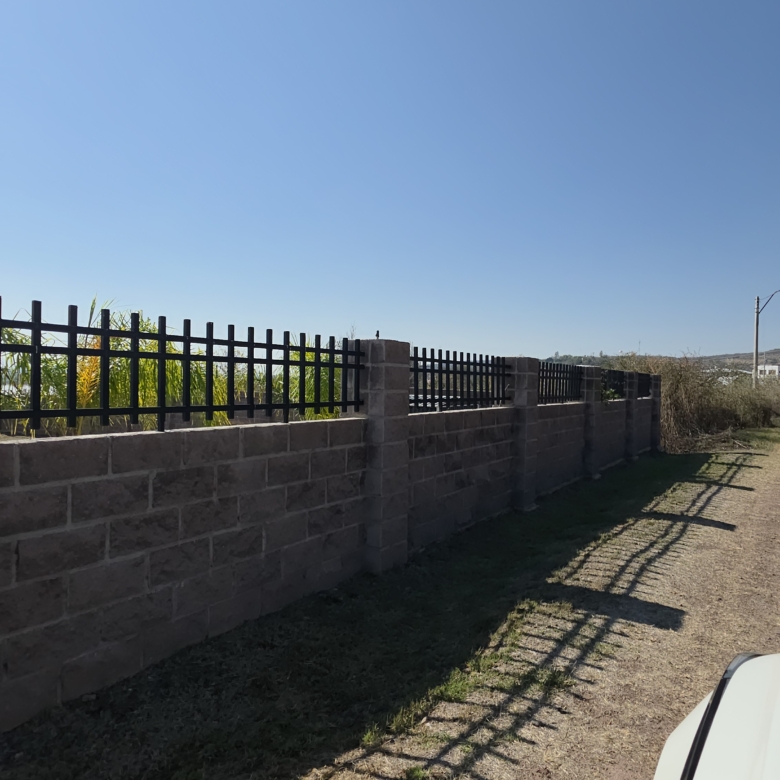 Muro de ladrillos con reja negra en terreno en venta en Cañada de Negros, Purísima del Rincón, Guanajuato