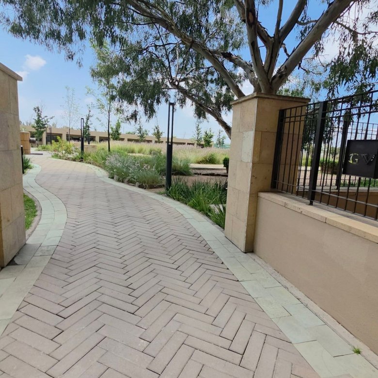 Camino pavimentado entre áreas verdes y jardines en el desarrollo Grand Valbuena León