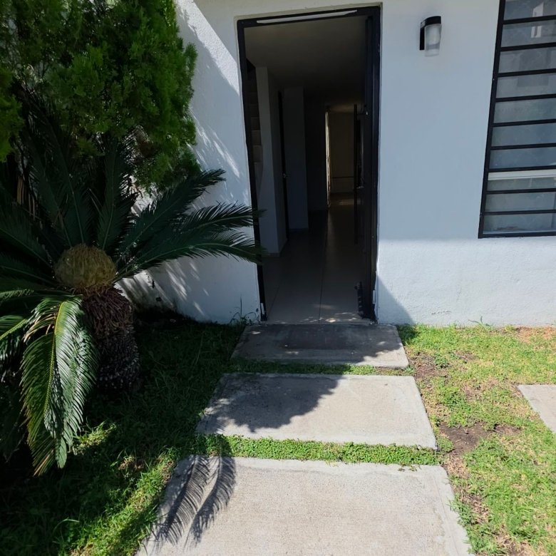 Fachada y acceso principal con jardin y huellas de concreto en casa en renta Residencial Oasis Leon Gto